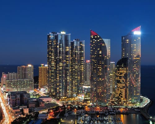 Rascacielos iluminados de Busan junto al mar al anochecer