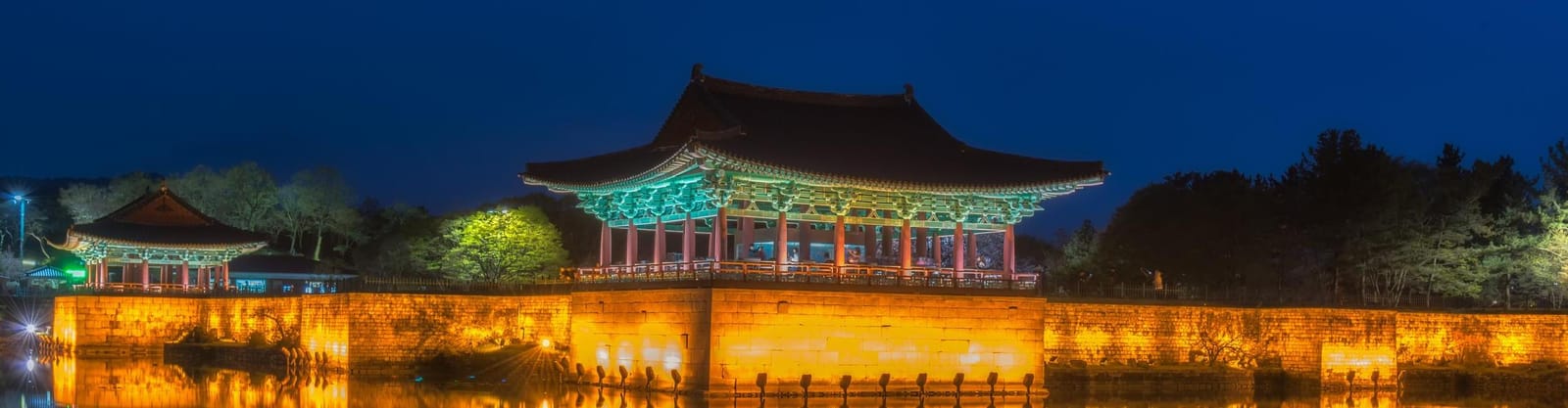 Pabellón tradicional iluminado de noche junto al agua en Gyeongju