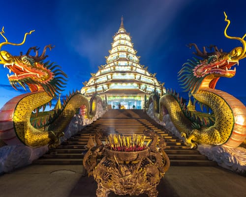 Templo blanco con dragones dorados en una escalinata de Chiang Rai