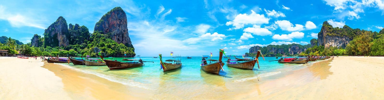 Playa de aguas turquesa con botes de cola larga en Krabi